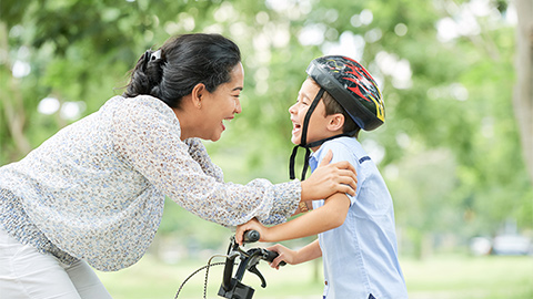 Mom teaching child to ride bicycle