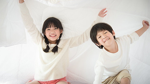 Siblings playing on bed